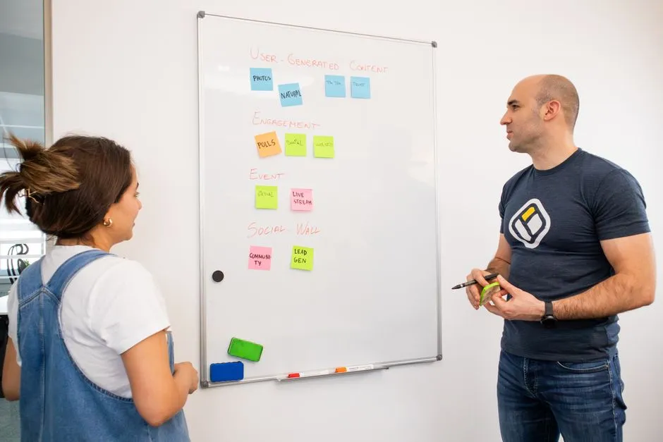 Two colleagues mapping out a plan on a whiteboard, illustrative of the cross-discipline planning an integrated marketing engagement requires.